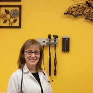 Dr. Maria Fain-Karpus, MD, pediatrician, smiling in her Woodland Hills medical office wearing a white coat and stethoscope